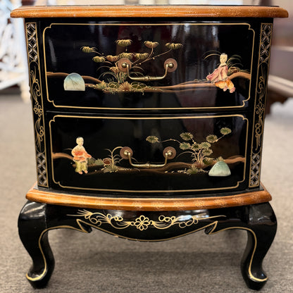Decorative black chest of drawers with gold accents and intricate designs on a neutral background