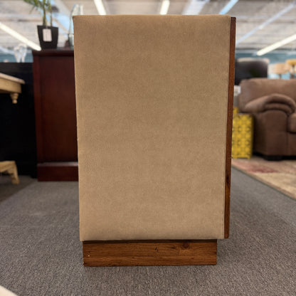 Beige upholstered chair with wooden base in a store setting