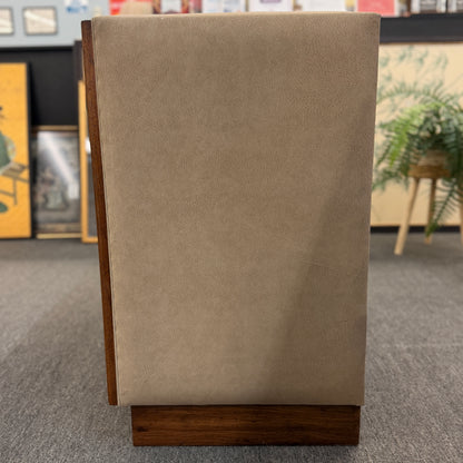 Beige textured box with wooden base on a gray carpeted floor