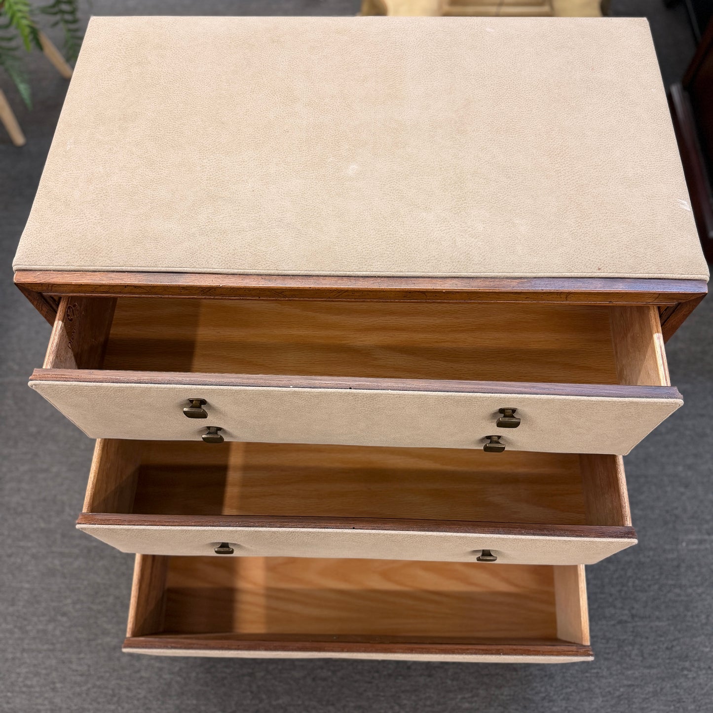 Wooden side table with two drawers on a gray floor.