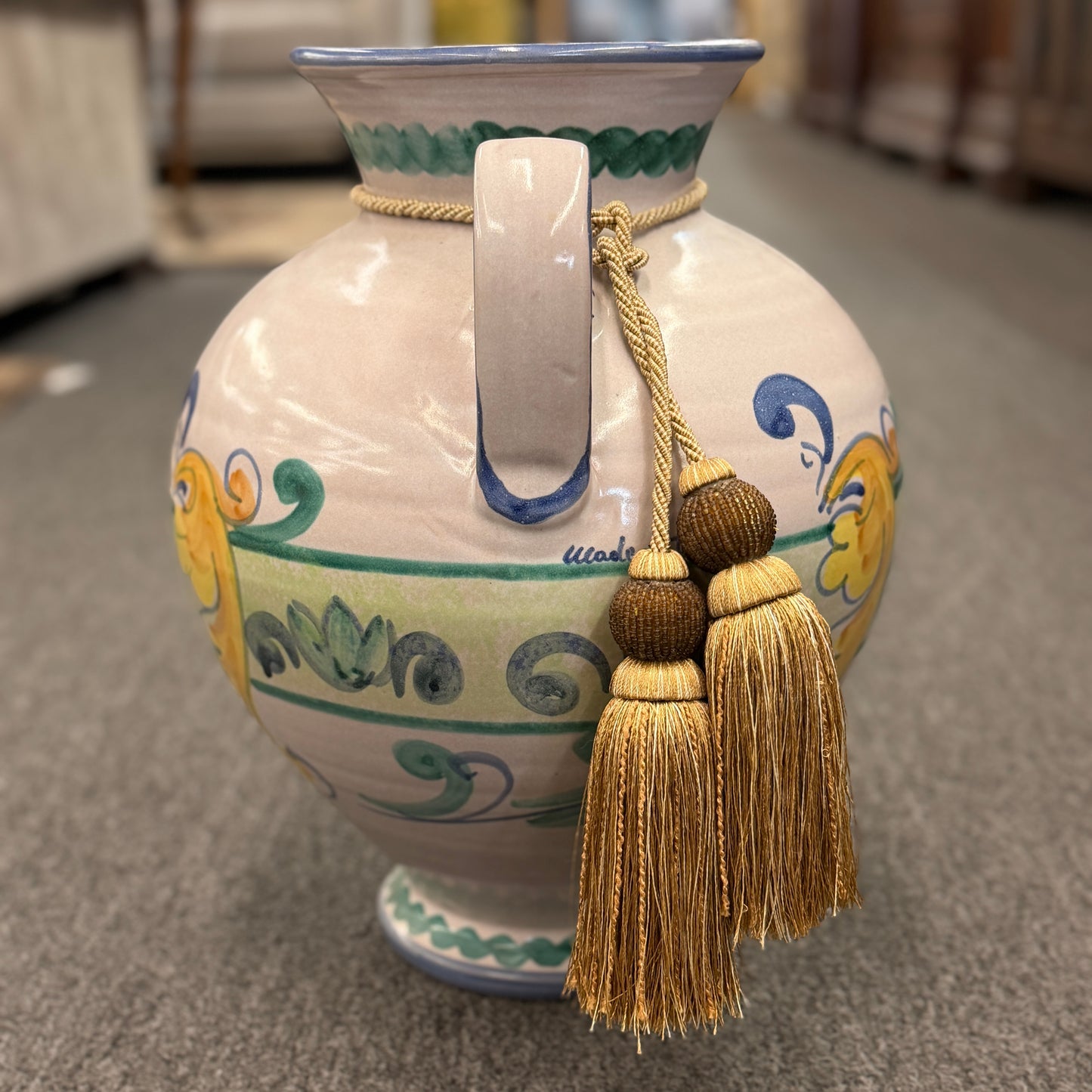 Decorative vase with tassels on a carpeted floor