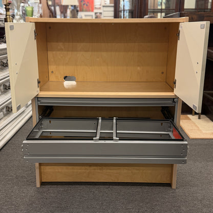 Wooden storage unit with open doors and drawers on a carpeted floor.