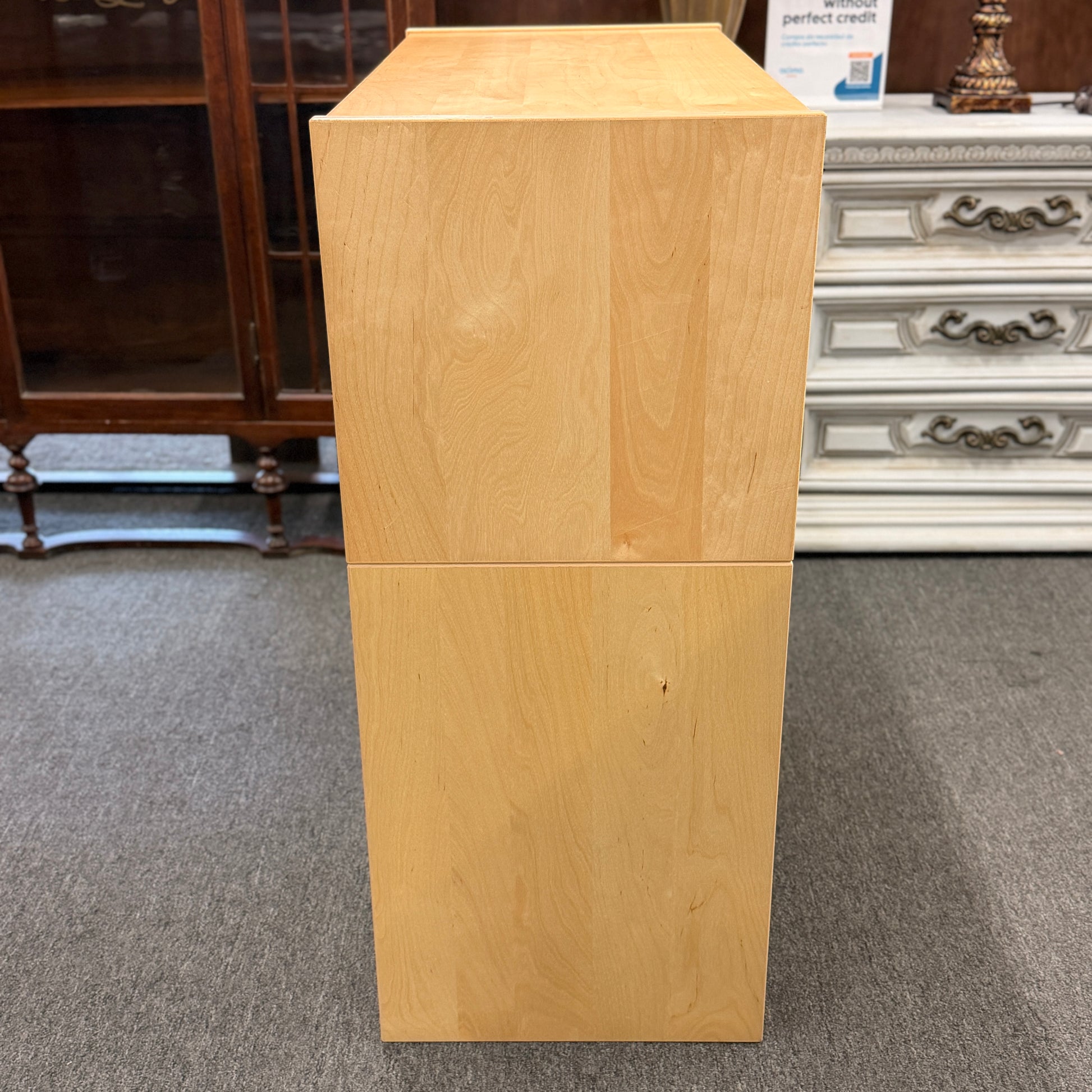 Wooden cabinet on a carpeted floor with furniture in the background