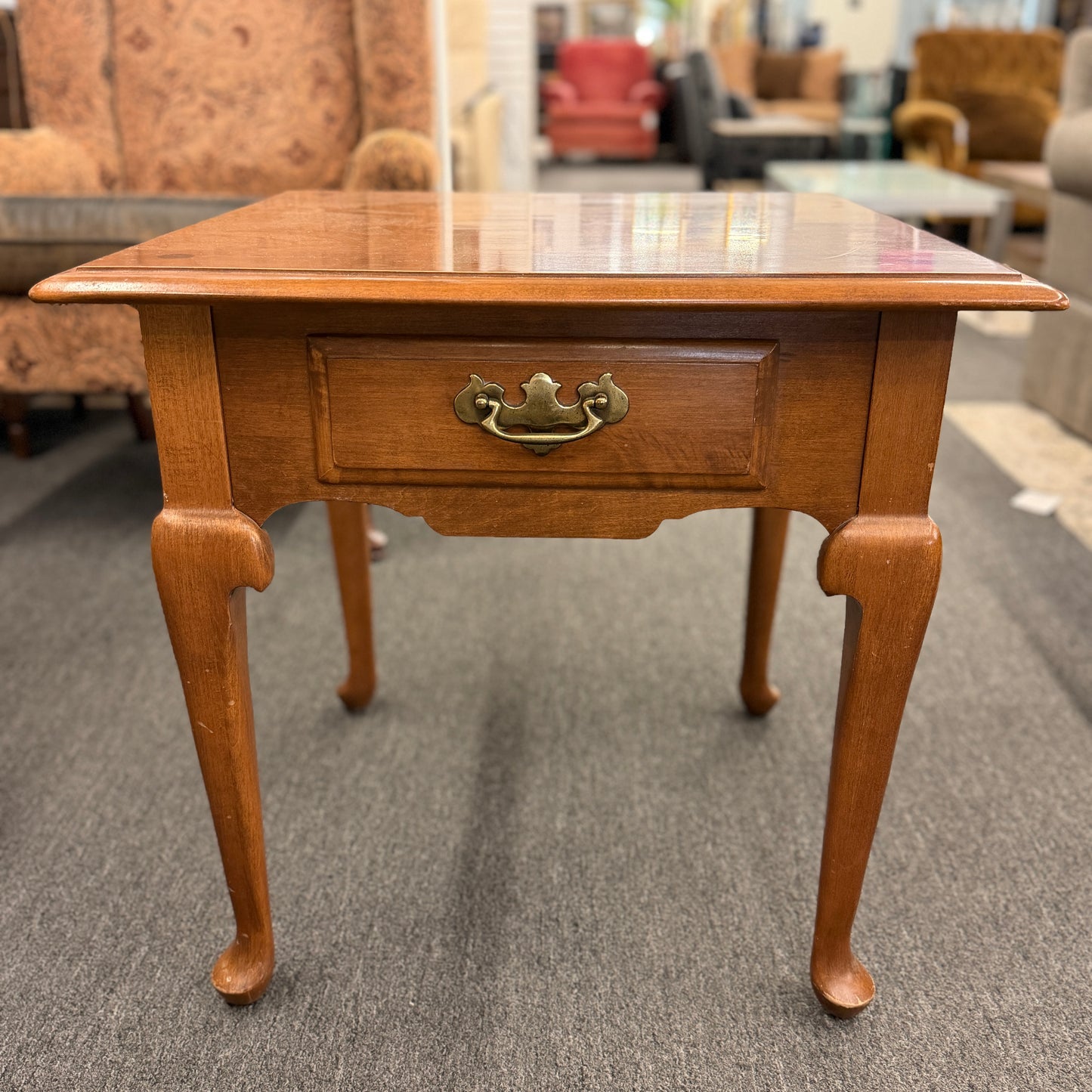 Wooden side table with a drawer in a furniture store setting