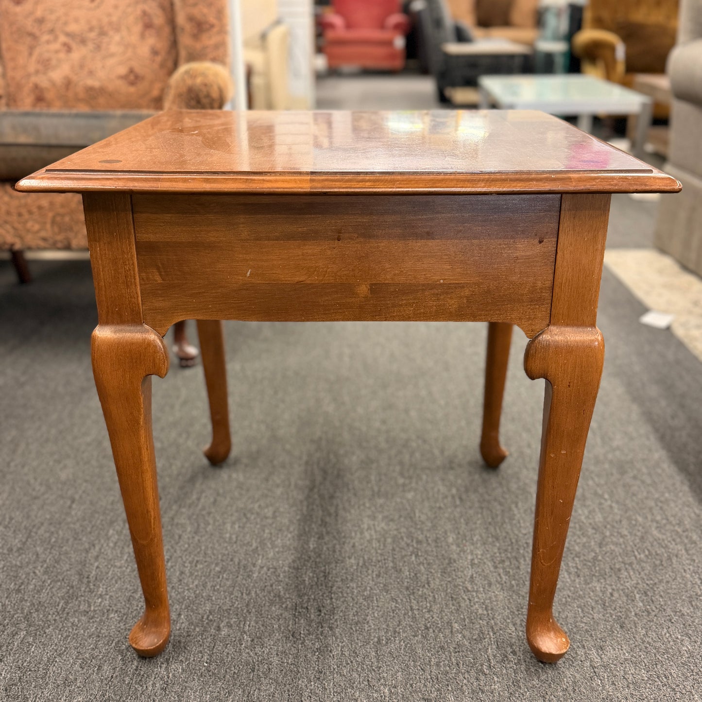 Wooden table with a reflective surface on a gray carpeted floor