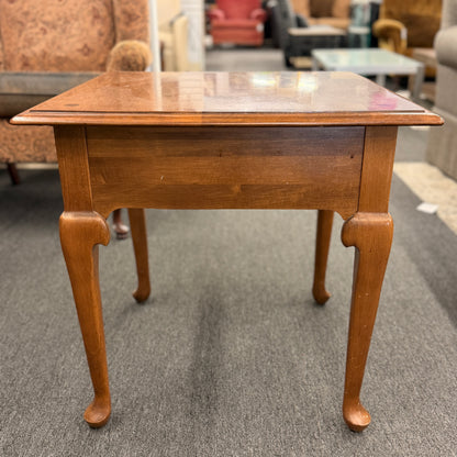 Wooden table with a reflective surface on a gray carpeted floor