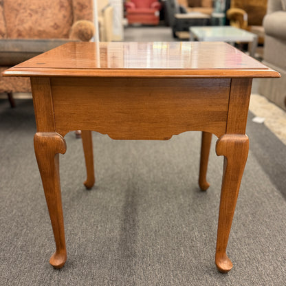 Wooden side table with a checkered surface in a furniture store setting