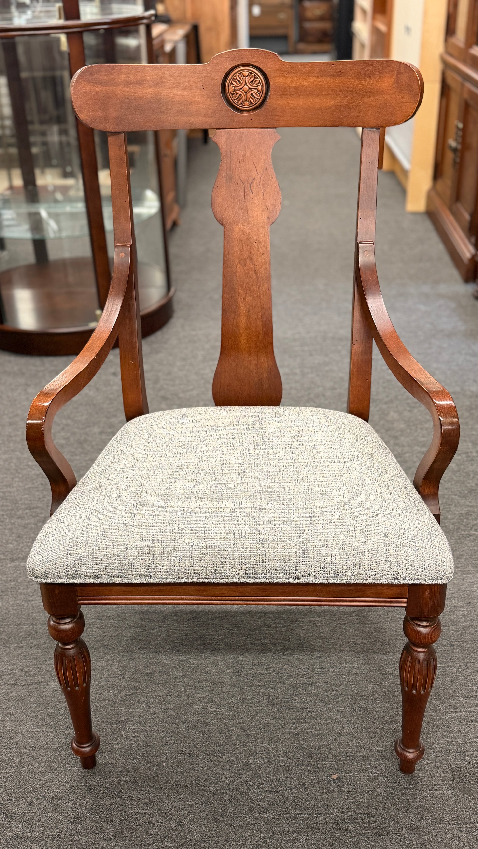 Wooden chair with a textured gray cushion on a carpeted floor