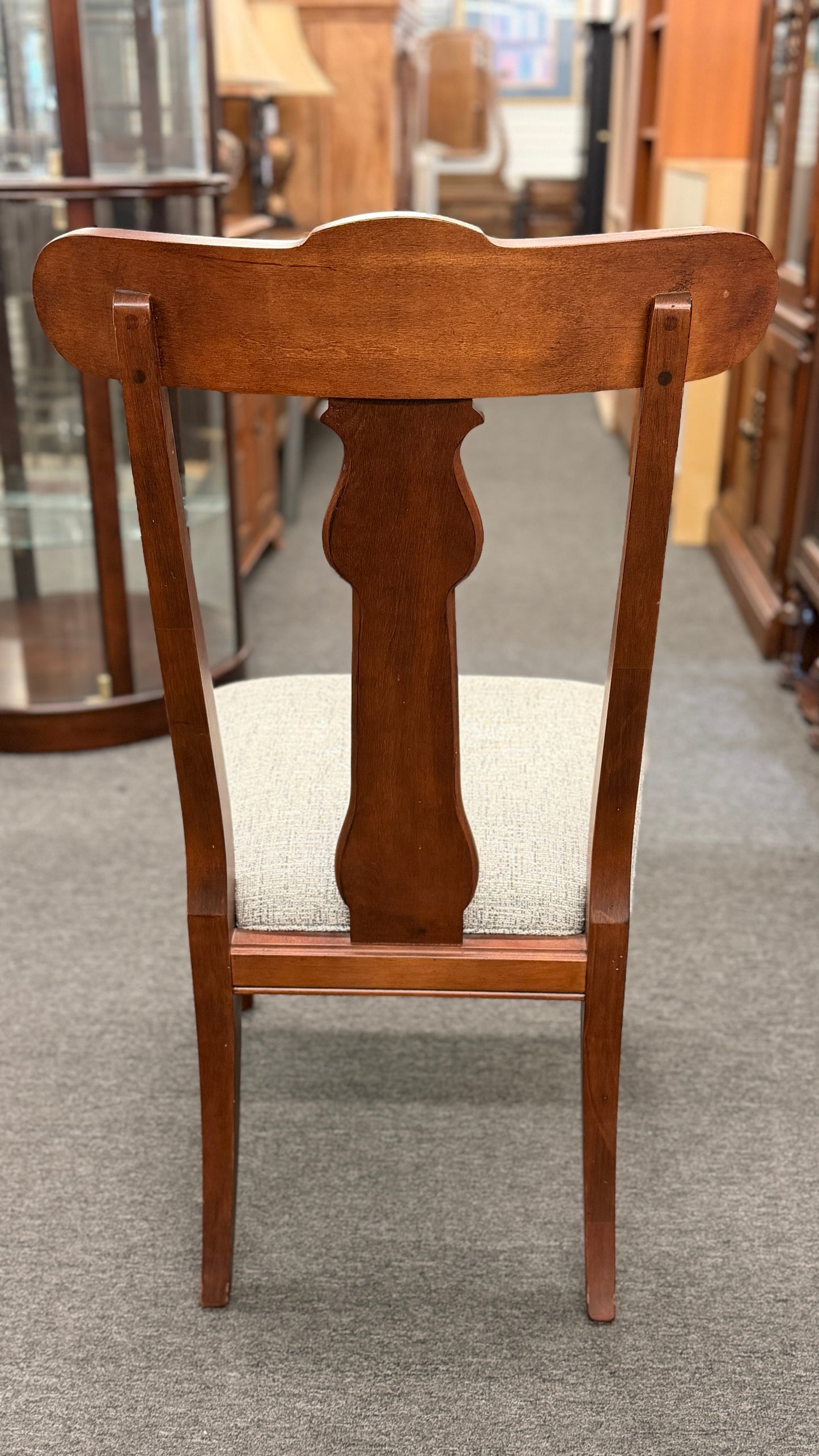 Wooden chair with a white cushion on a gray floor