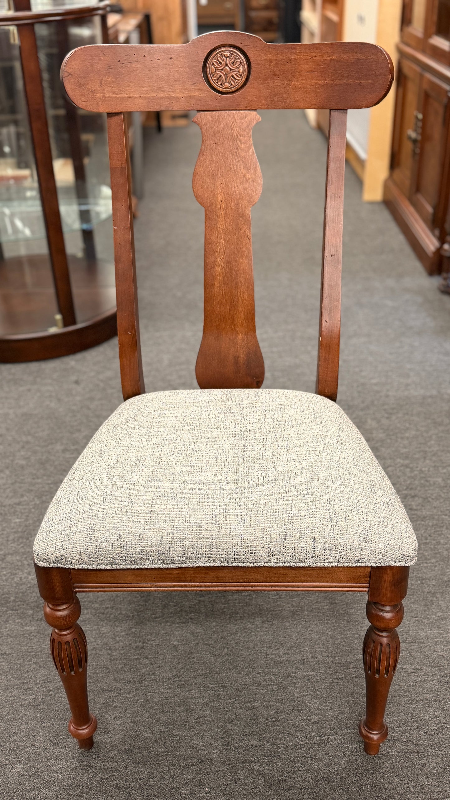 Wooden chair with a patterned cushion on a gray floor