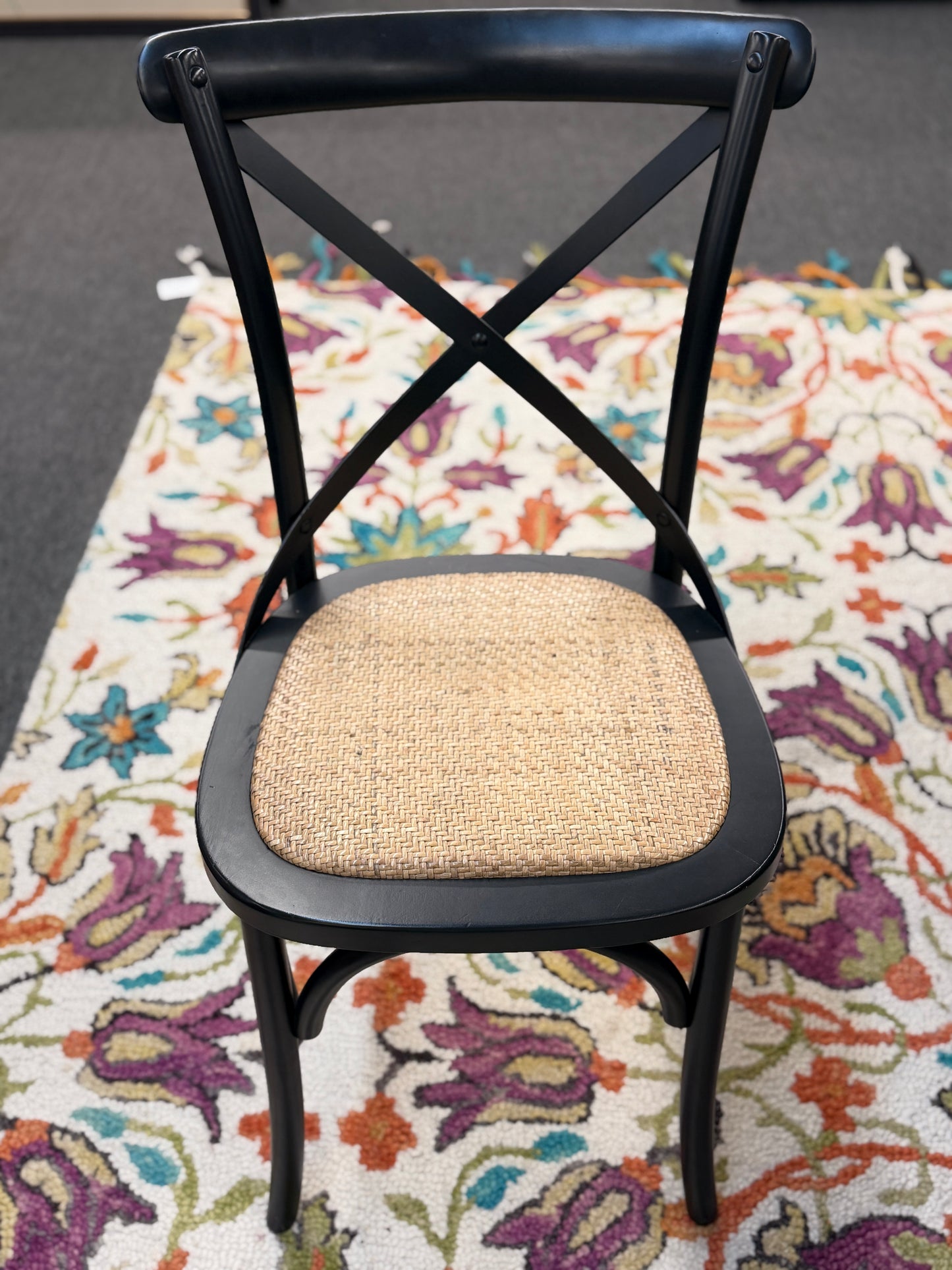 Black chair with a woven seat on a colorful floral rug
