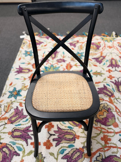 Black chair with a woven seat on a colorful floral rug