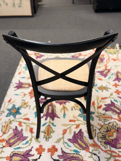 Black chair with woven seat on a colorful floral rug