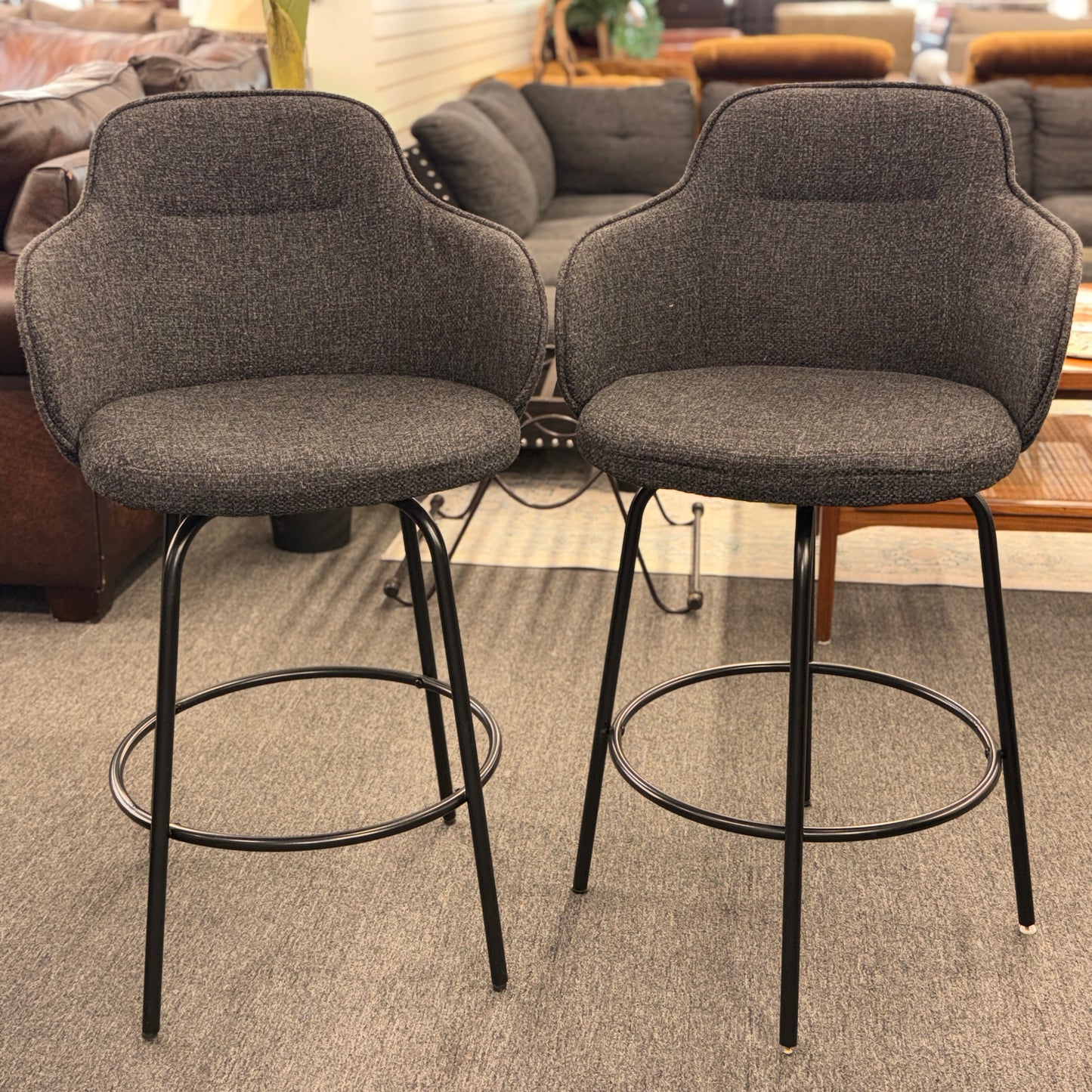 Two gray bar stools with black metal legs in a room setting.