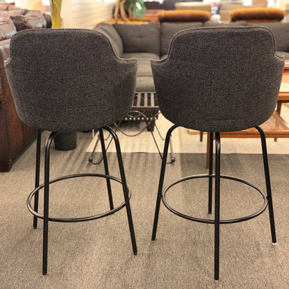 Two gray bar stools with black metal legs in a room with furniture.