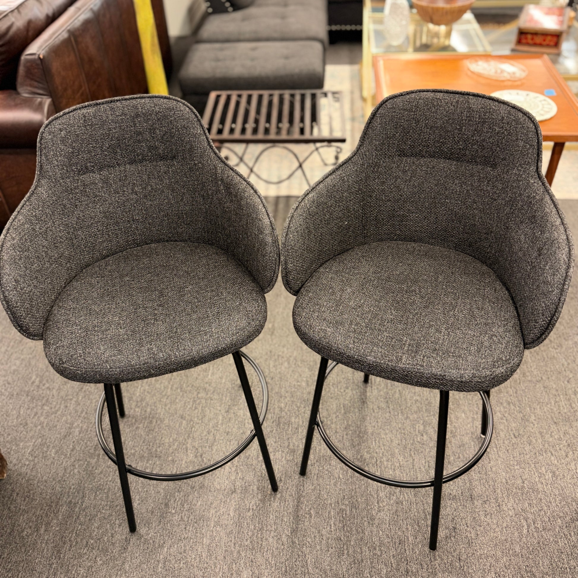Two gray bar stools with black metal legs in a room setting.