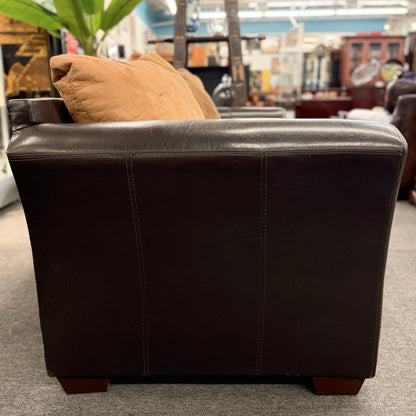 Brown leather armchair with a pillow in a store setting
