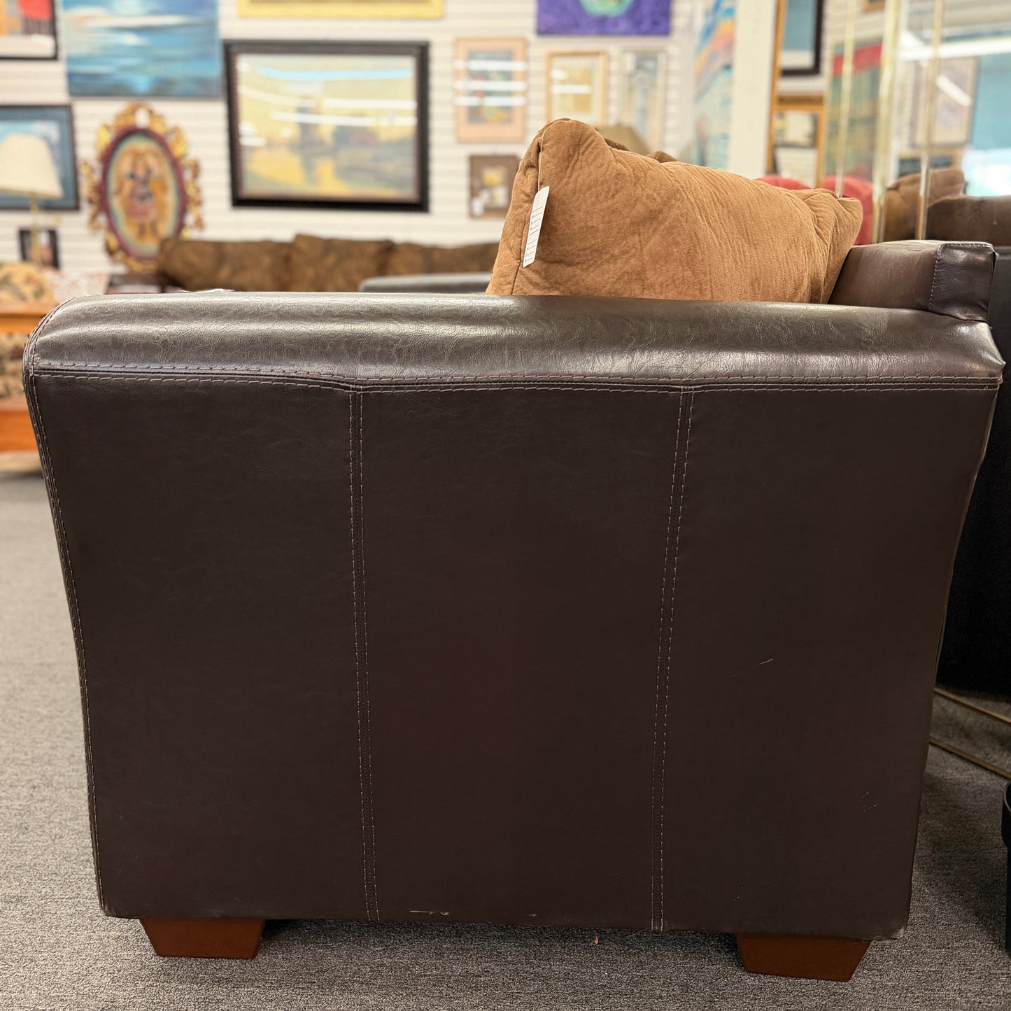 Brown leather sofa with a brown pillow in a store setting