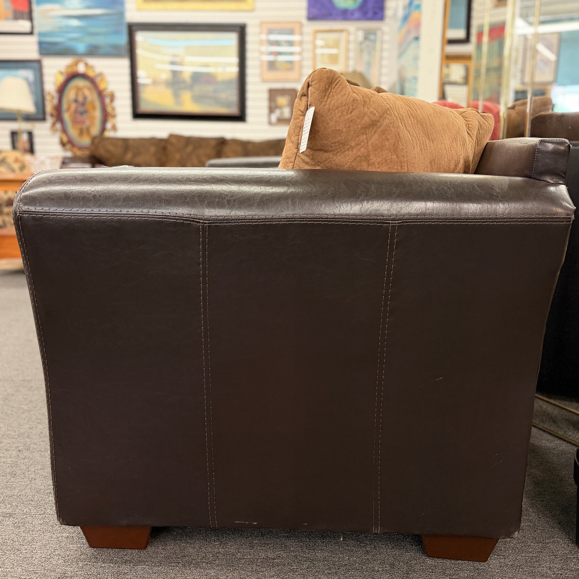 Brown leather sofa with a brown pillow in a store setting