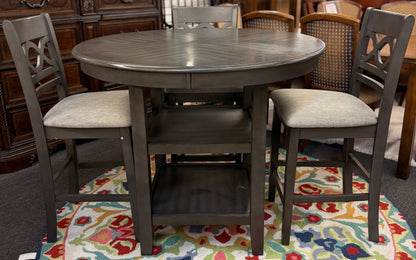 Round wooden dining table with four chairs on a patterned rug in a furniture store.