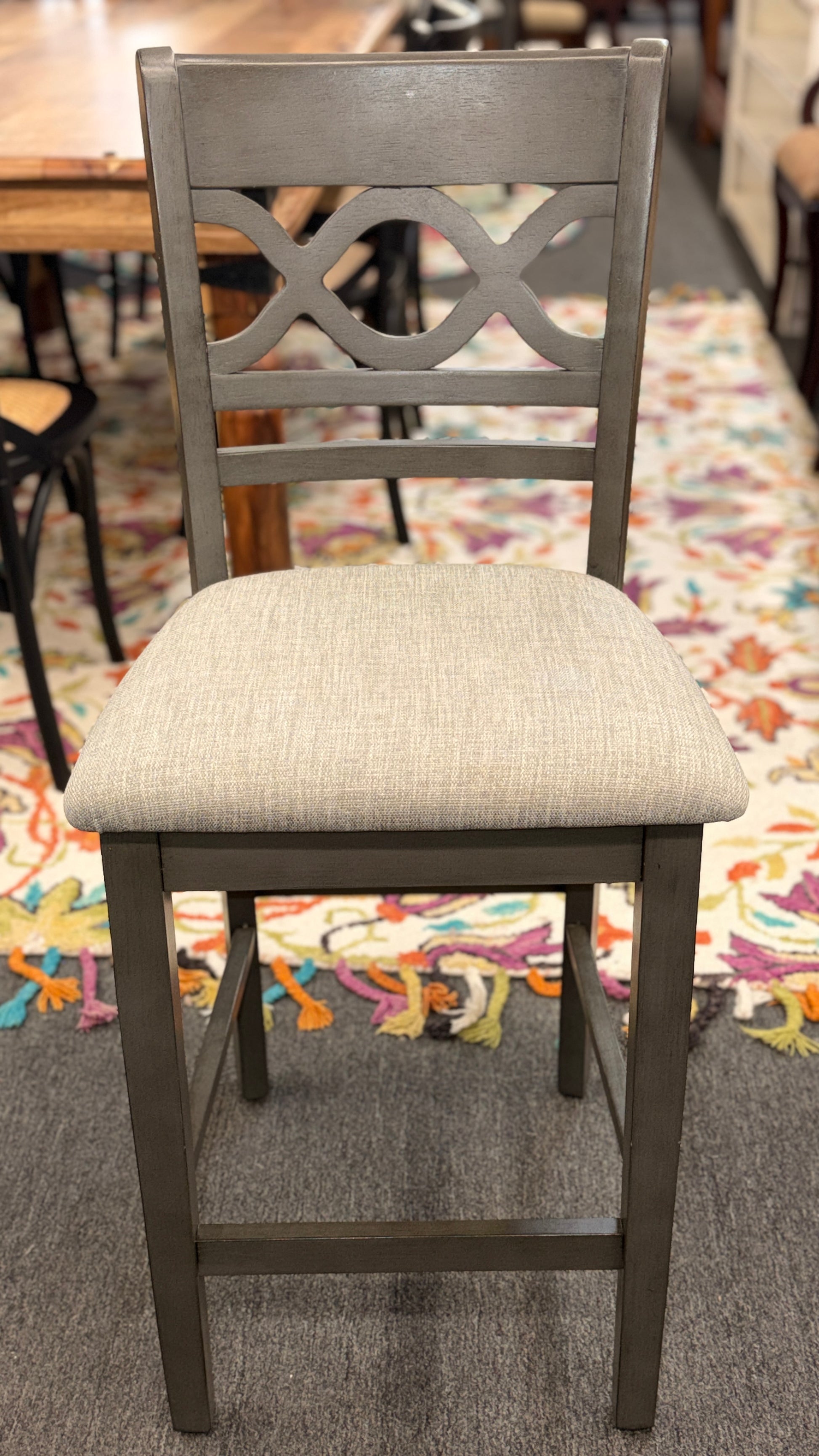 Gray chair with a patterned cushion on a carpeted floor.