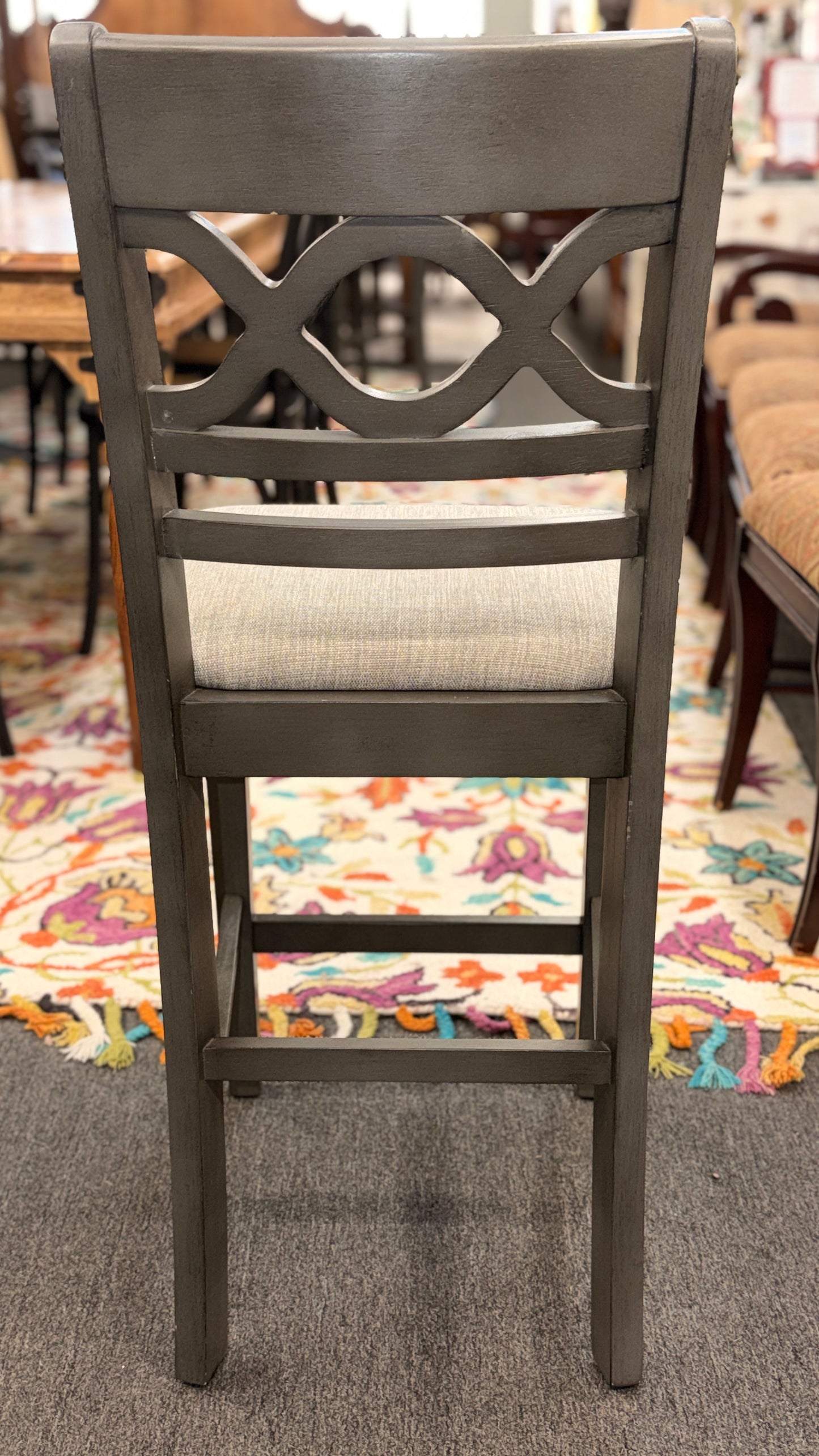 Wooden chair with a decorative backrest on a carpeted floor.