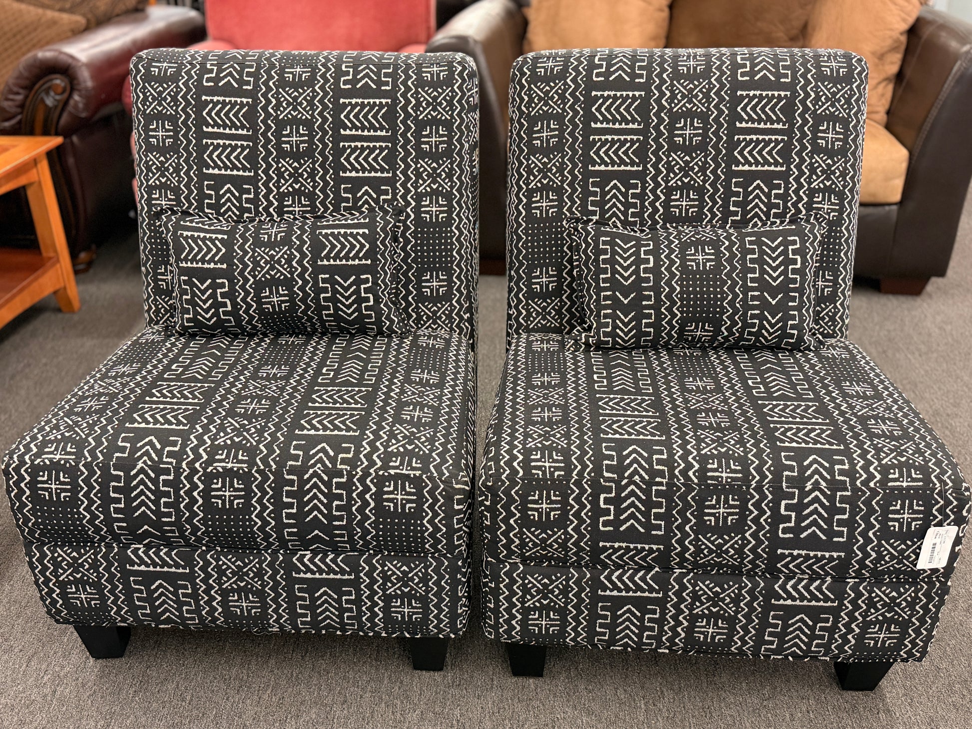 Two patterned chairs on a carpeted floor with furniture in the background