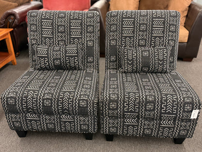 Two patterned chairs on a carpeted floor with furniture in the background