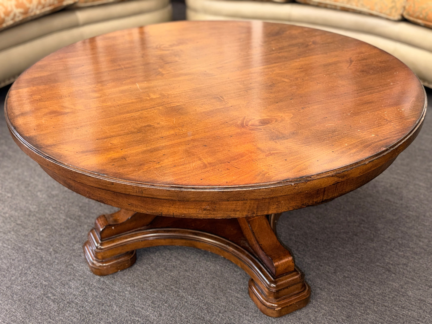 Round wooden table with a textured surface on a gray floor.
