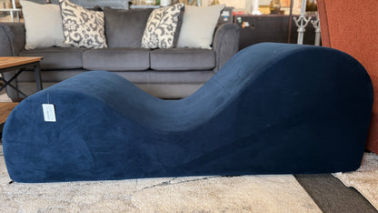 Blue curved cushion on a carpeted floor with a sofa and pillows in the background