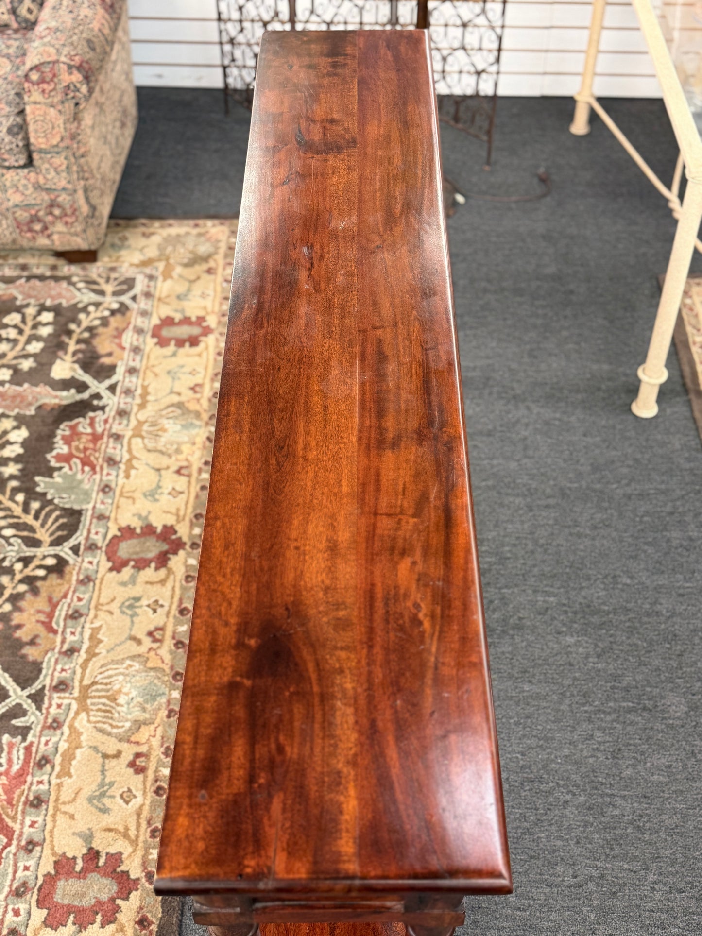 Long wooden table in a room with a patterned rug and furniture.