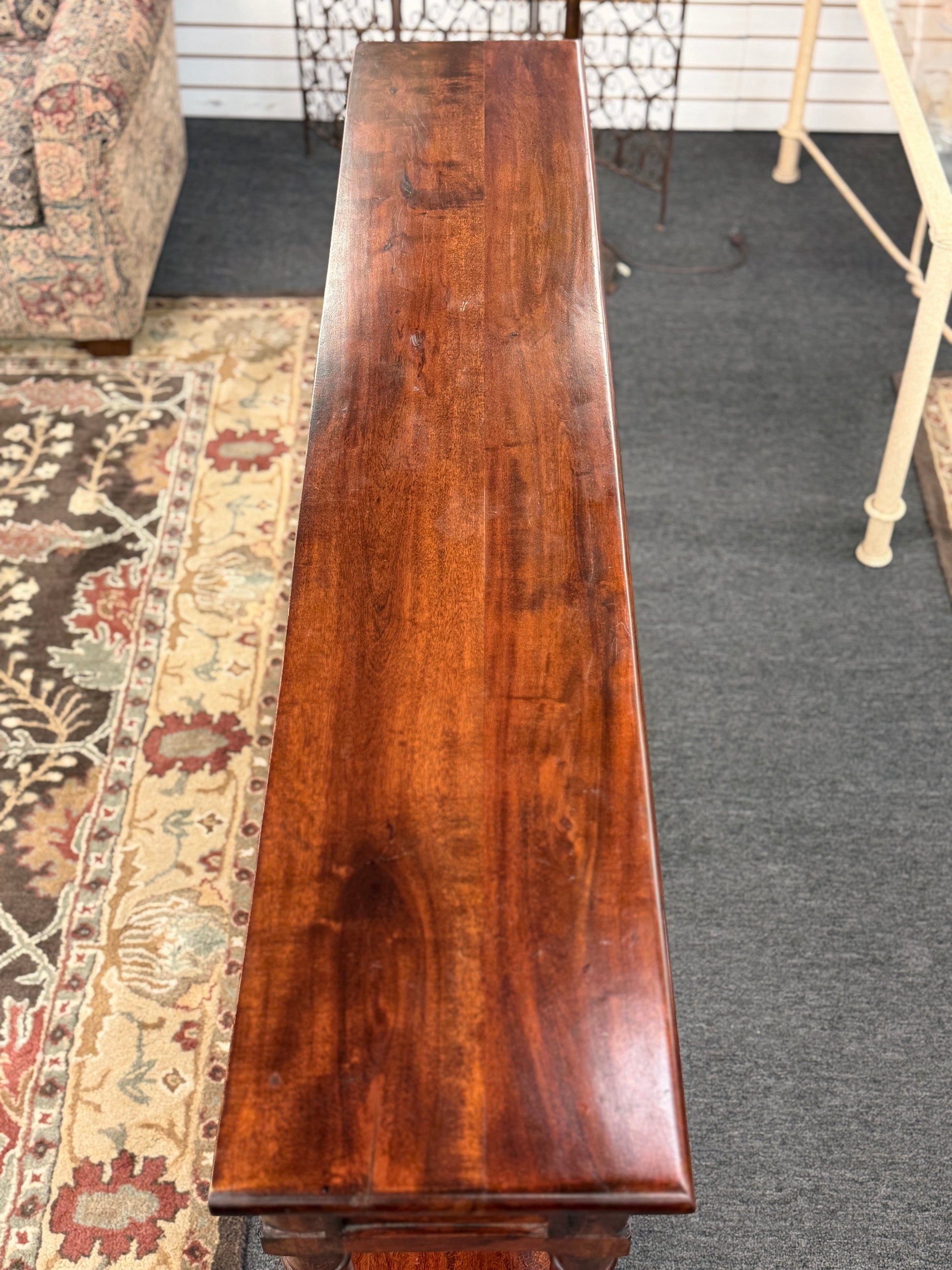 Long wooden table in a room with a patterned rug and furniture.