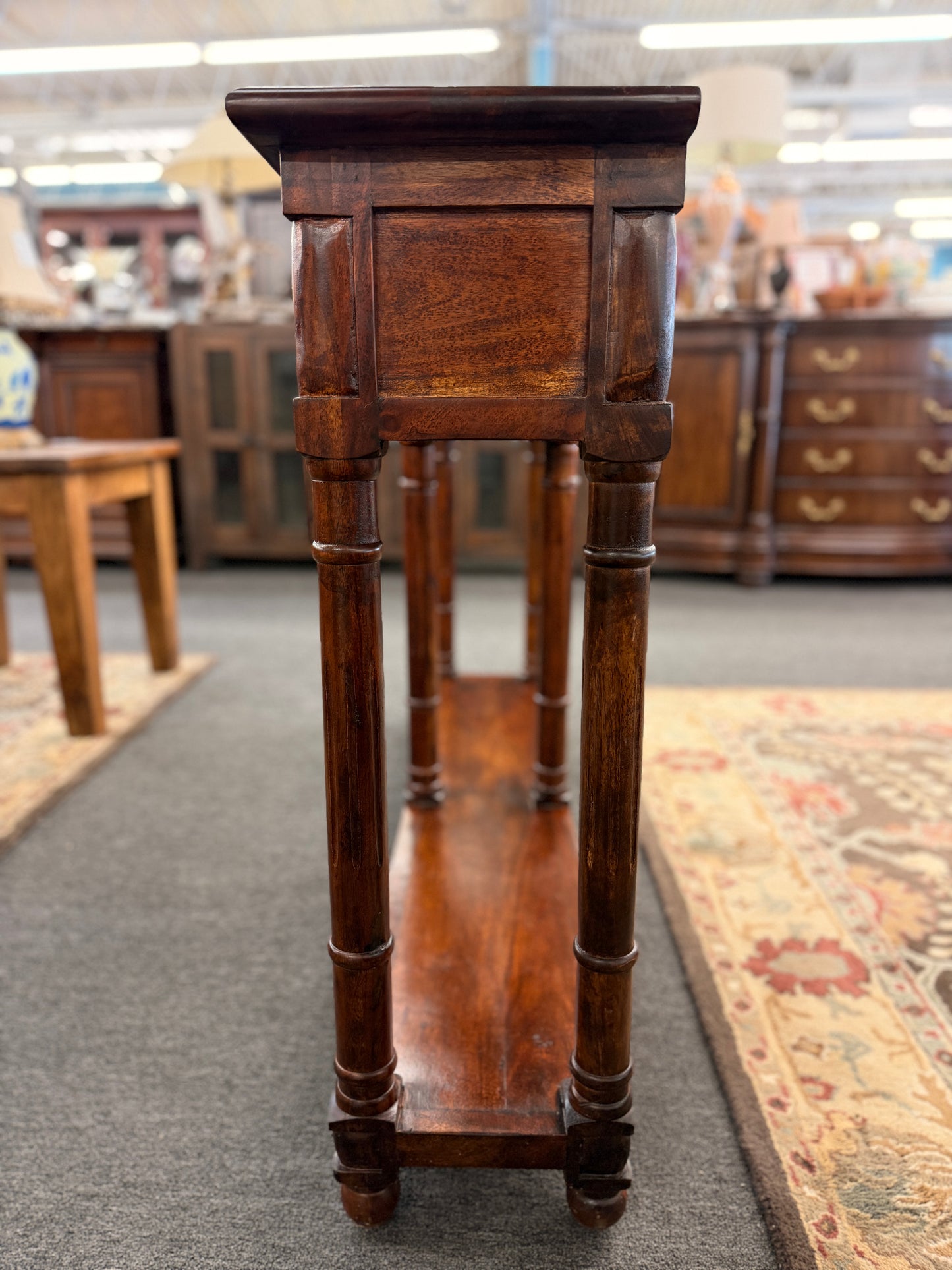 Wooden pedestal in a store setting with blurred furniture in the background