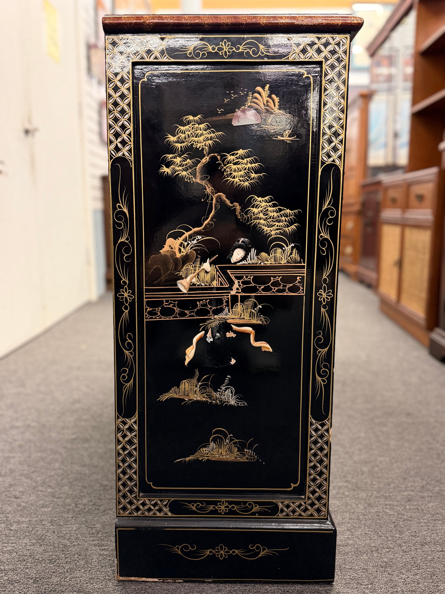 Decorative black cabinet with gold and white designs in a store setting