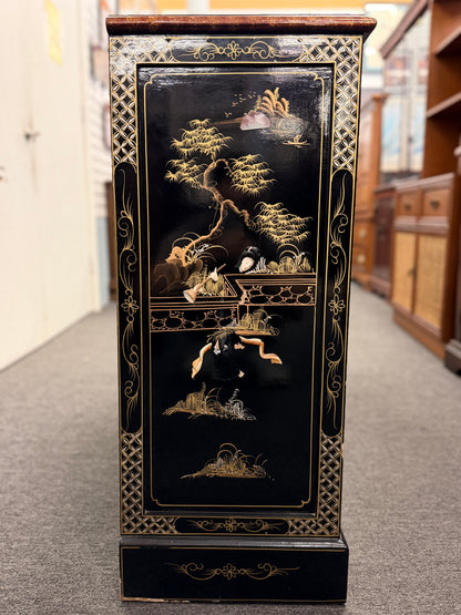 Decorative black cabinet with gold and white designs in a store setting