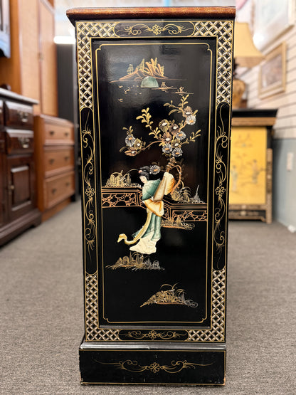 Decorative black pedestal with intricate gold and green designs in a store setting