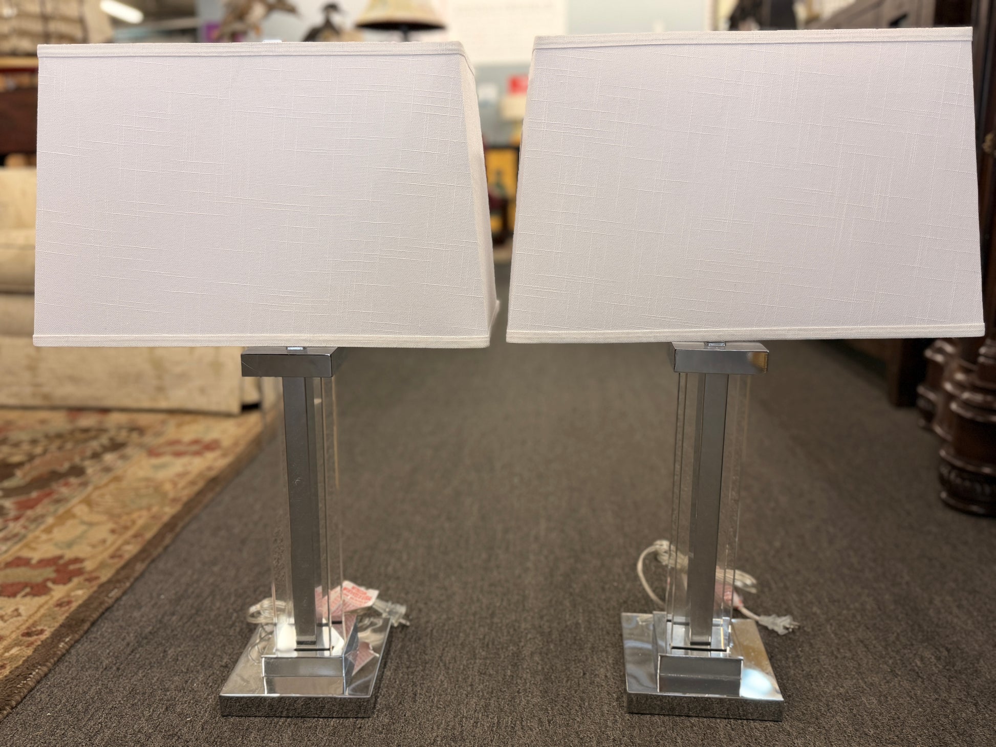 Two table lamps with white lampshades on a carpeted floor.
