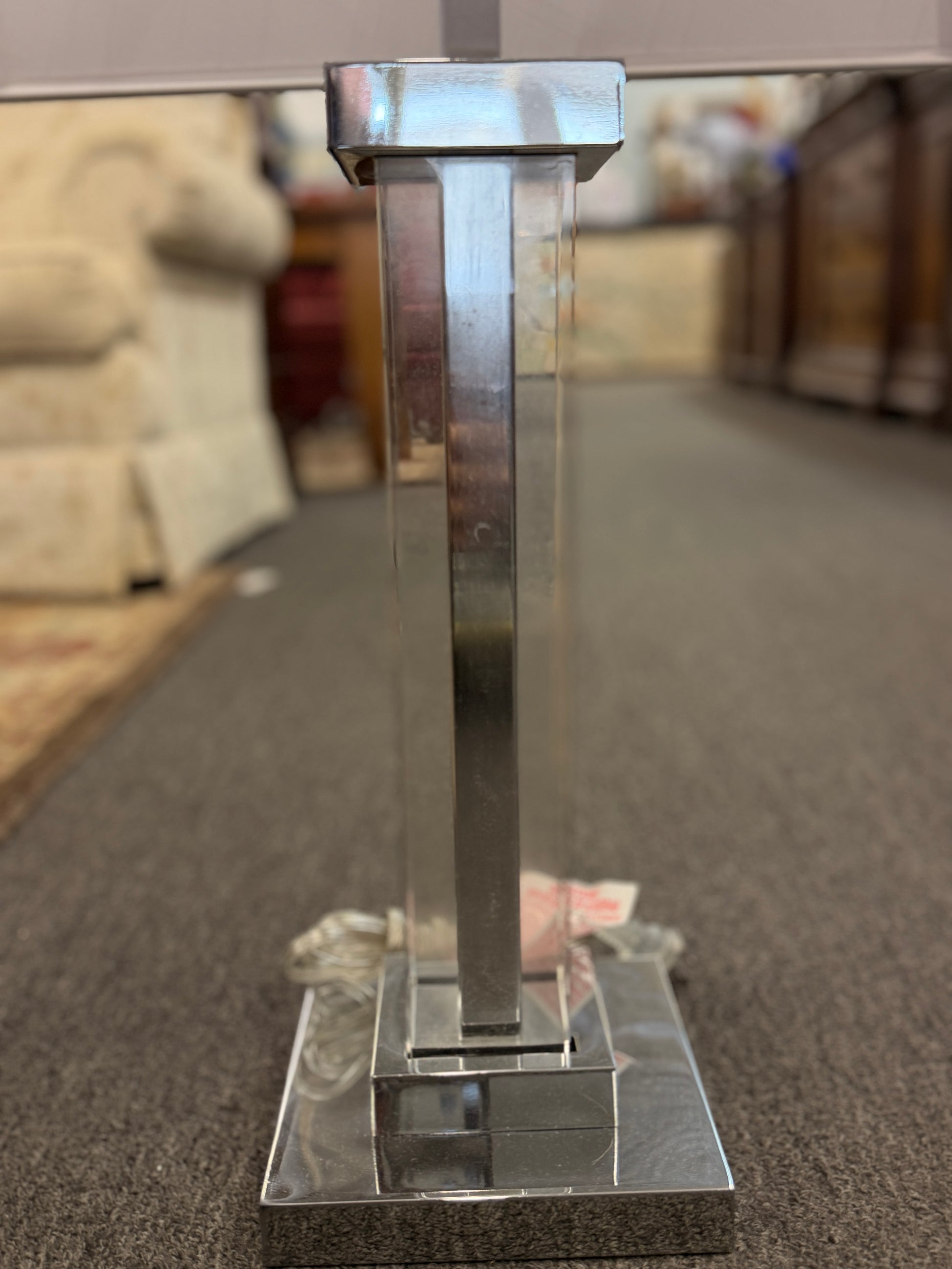 Metallic stand or pedestal on a carpeted floor with a blurred background