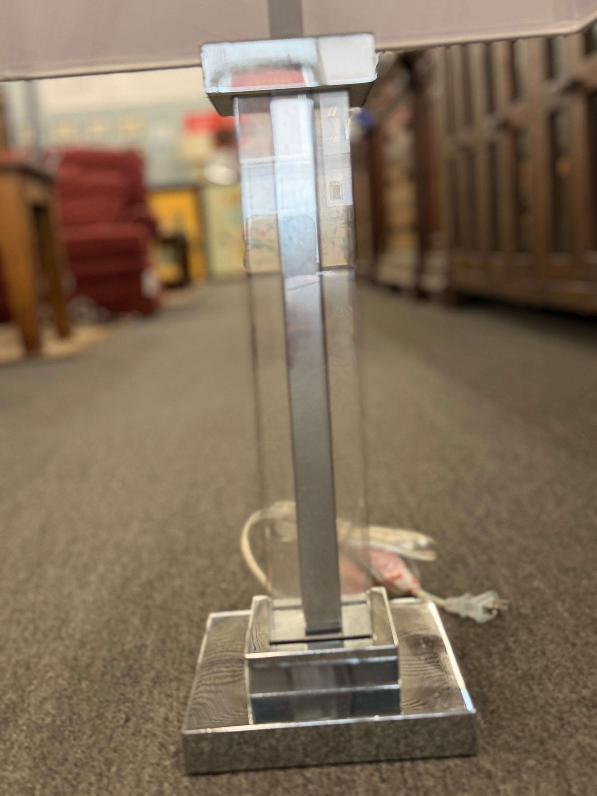 Metallic stand on a reflective surface with a blurred indoor background