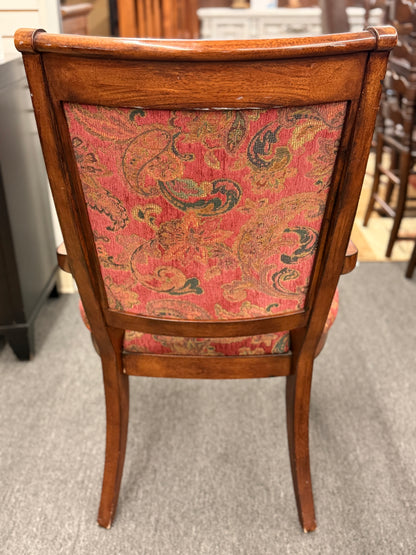 Wooden chair with paisley-patterned fabric backrest on a gray floor.