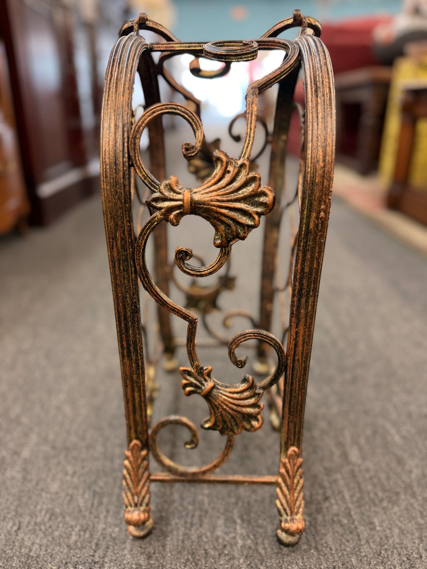Decorative metal stand with intricate designs on a carpeted floor.