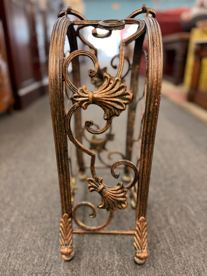 Decorative metal stand with intricate designs on a carpeted floor.