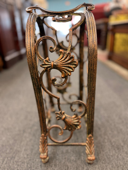 Decorative metal stand with intricate designs on a carpeted floor.
