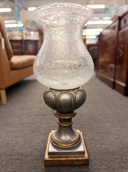 Decorative lamp with a textured glass shade and metal base in an indoor setting.