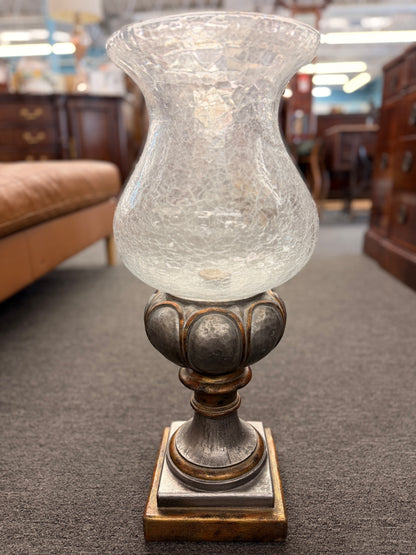 Decorative lamp with a textured glass shade on a wooden base in an indoor setting.