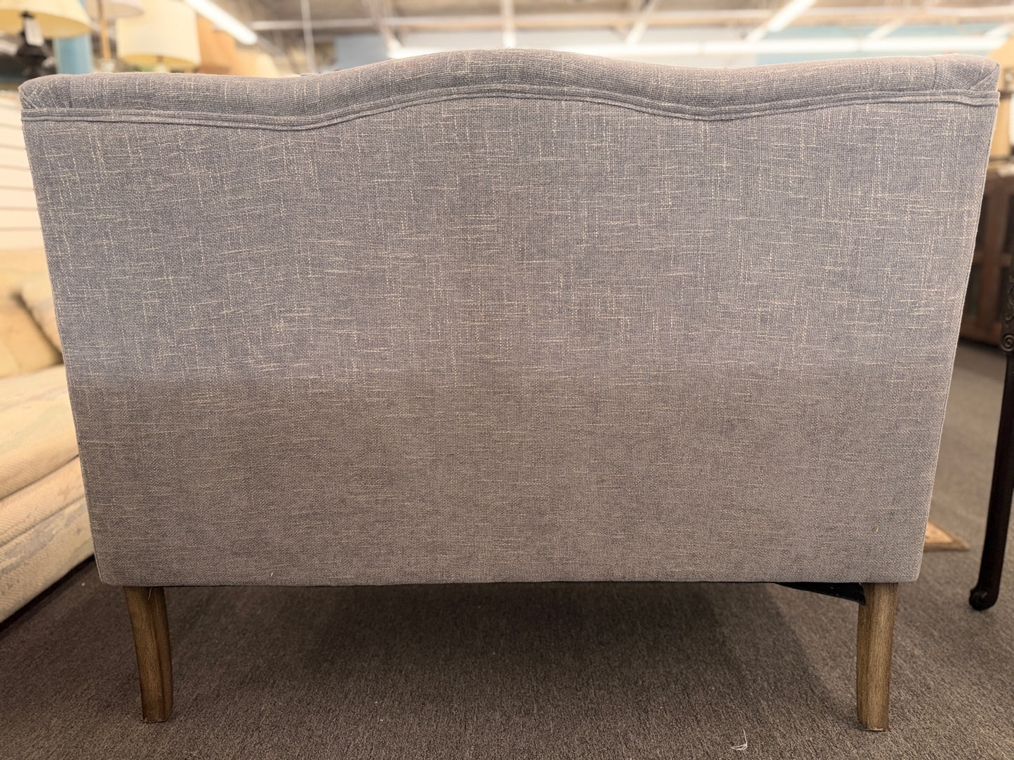Gray upholstered chair with wooden legs in a store setting
