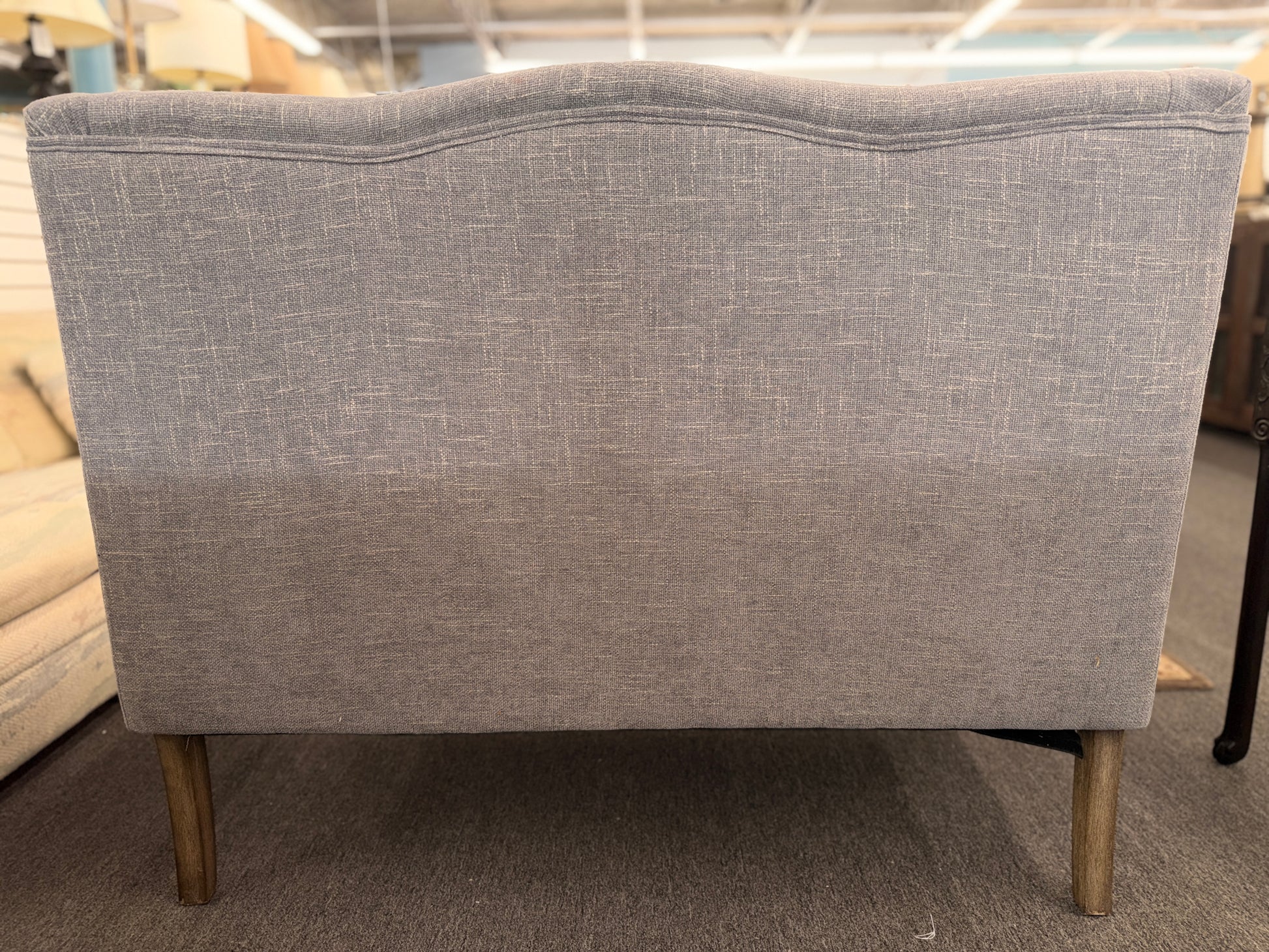 Gray upholstered chair with wooden legs in a store setting