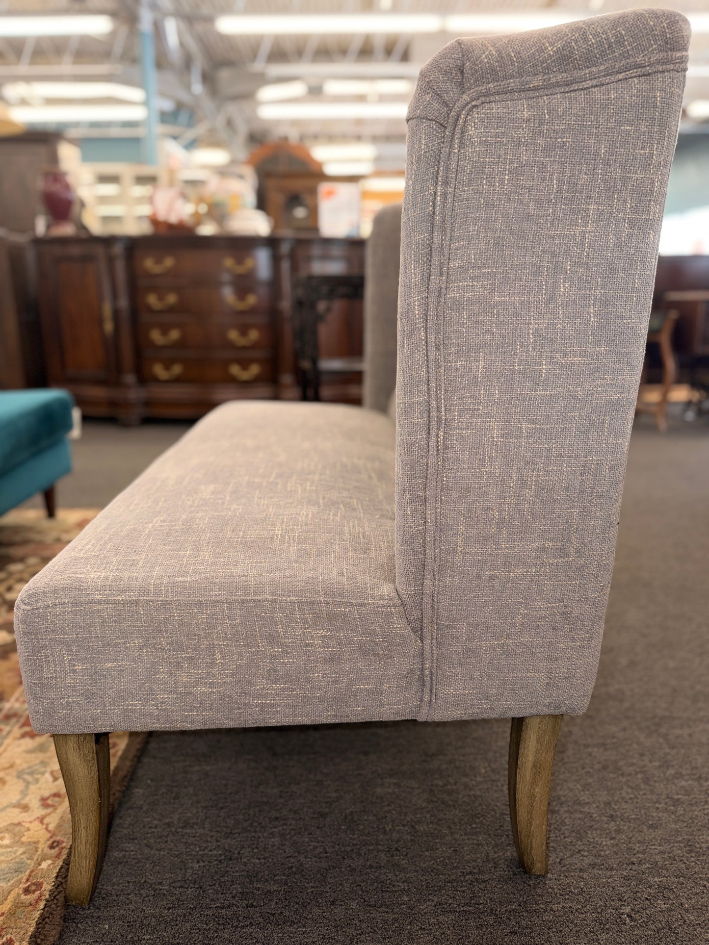 Gray upholstered chair with wooden legs in a store setting