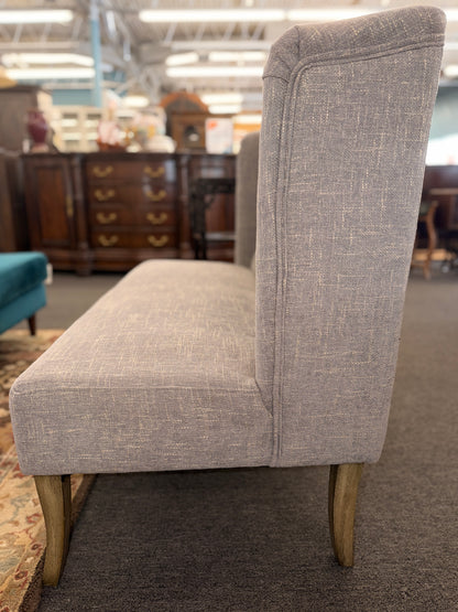 Gray upholstered chair with wooden legs in a store setting