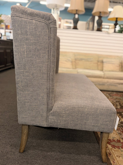 Gray upholstered chair with wooden legs in a showroom setting